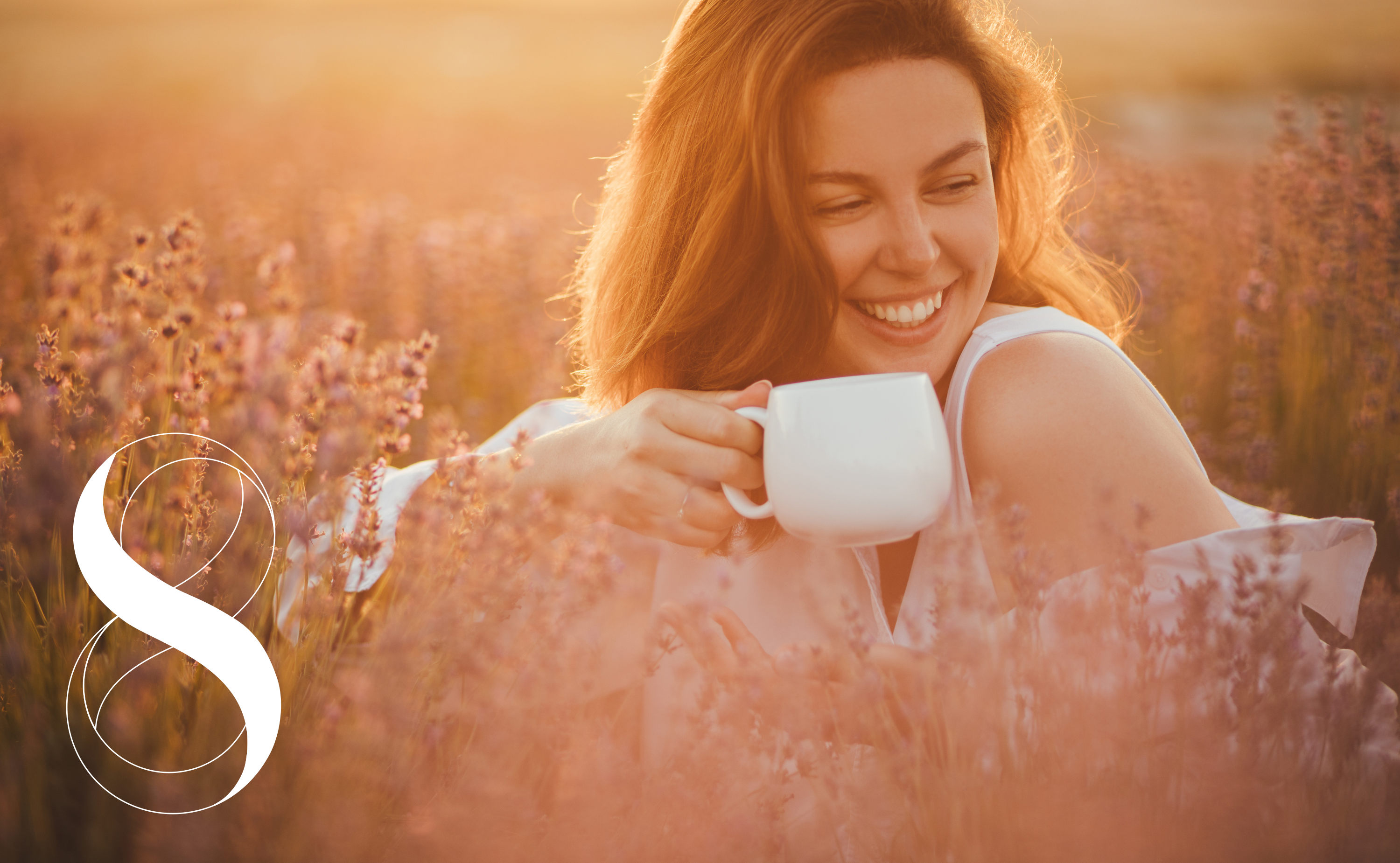 Eine lachende Frau sitzt bei Sonnenuntergang in einem Feld voller Kräuter und hält eine Tasse in den Händen. Ein Symbolfoto von Life Light zur Kraft fermentierter Kräuter.