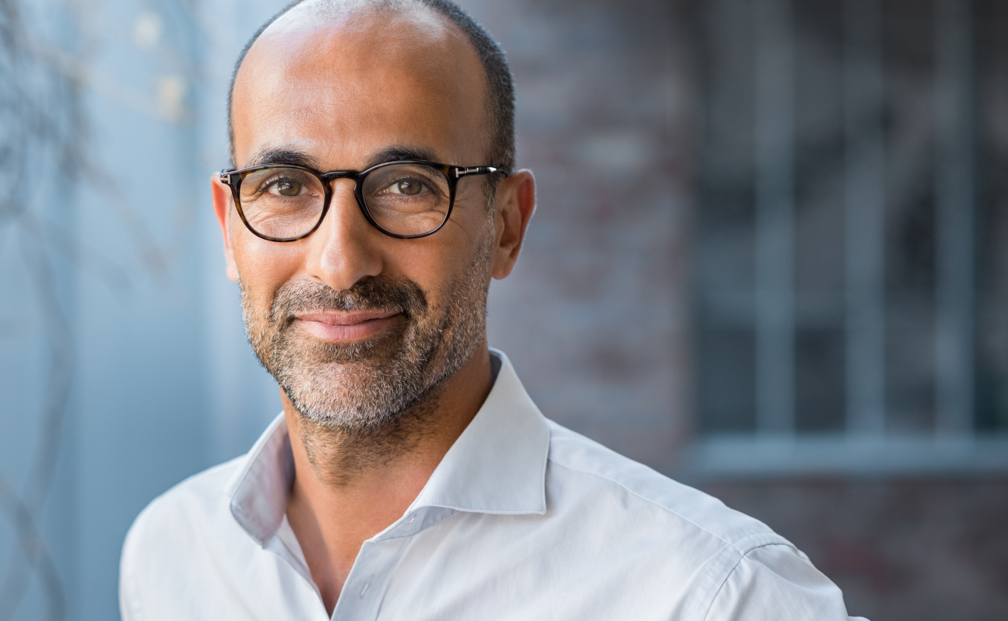 Ein Mann mit Brille und Bart lächelt in die Kamera.Ein Symbolfoto für Männergesundheit in Bezug auf die Prostata.